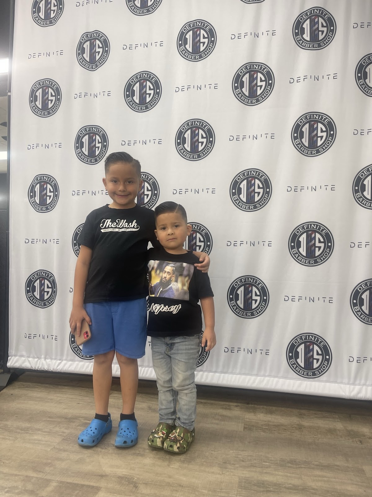 Two boys showing fresh cuts in front of Definite backdrop