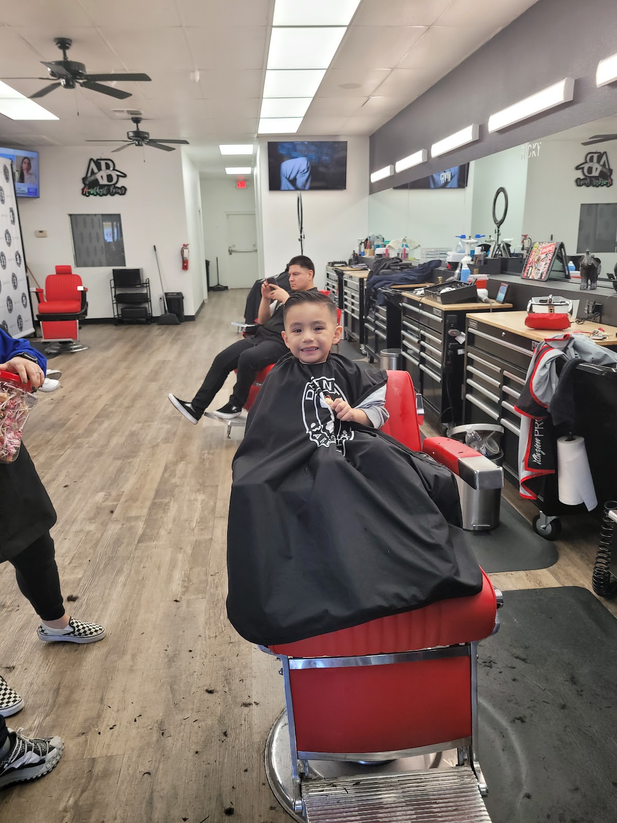 Young boy smiling in red barber chair inside shop